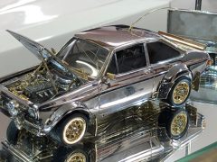 Een zilveren Ford speelgoedauto staat tentoongesteld in een glazen vitrine en rijdt niet.