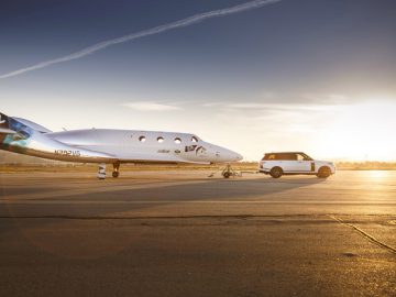 Een kleine Range Rover staat geparkeerd naast een ruimteschip.