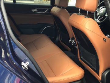 Het interieur van een Alfa Romeo Giulia Veloce met bruin lederen stoelen.