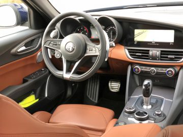 Het interieur van een Alfa Romeo Giulia Veloce met bruin lederen stoelen en stuurwiel.