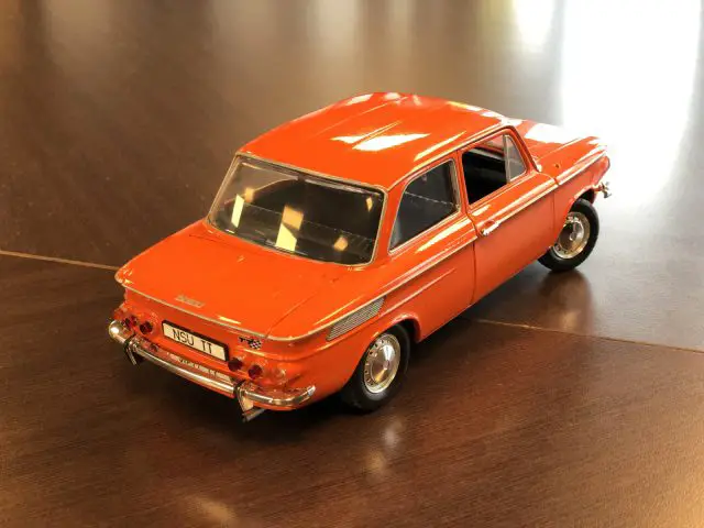 Een NSU 1000 TT oranje speelgoedauto op een houten tafel.