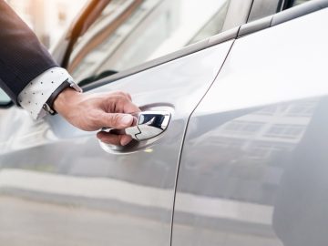 Een zakenman opent de deur van een auto om te kopen.