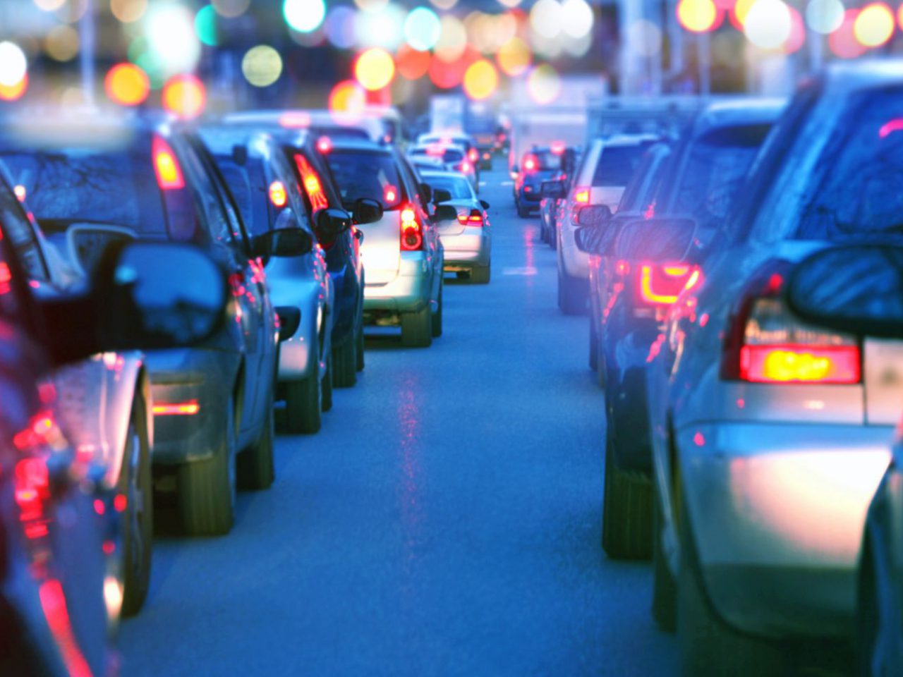 Een wazig beeld van auto's in een file, nadenkend over autobezit.