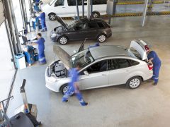Autohandelmonteurs werken aan een auto in een garage.
