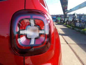 De achterkant van een rode Dacia Duster TCe 130 met een kruis erop.