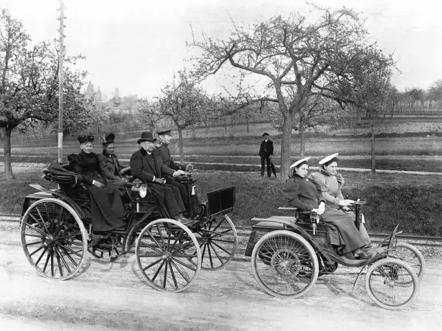 Een zwart-witfoto van een groep mensen rijdend in een Benz Velocipede.