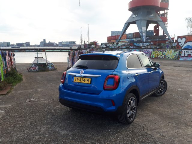 Een blauwe Fiat 500X Opening Edition geparkeerd voor een gebouw.