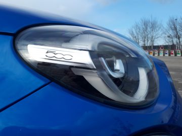 Een close-up van de koplamp van een Fiat 500X Opening Edition-auto.