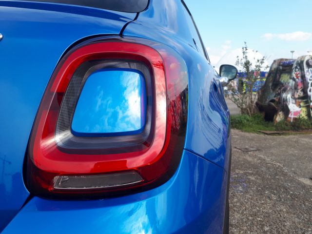De achterkant van een blauwe Fiat 500X Opening Edition met een rood achterlicht.