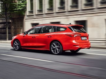 Een rode Ford Focus ST rijdt door een stadsstraat.