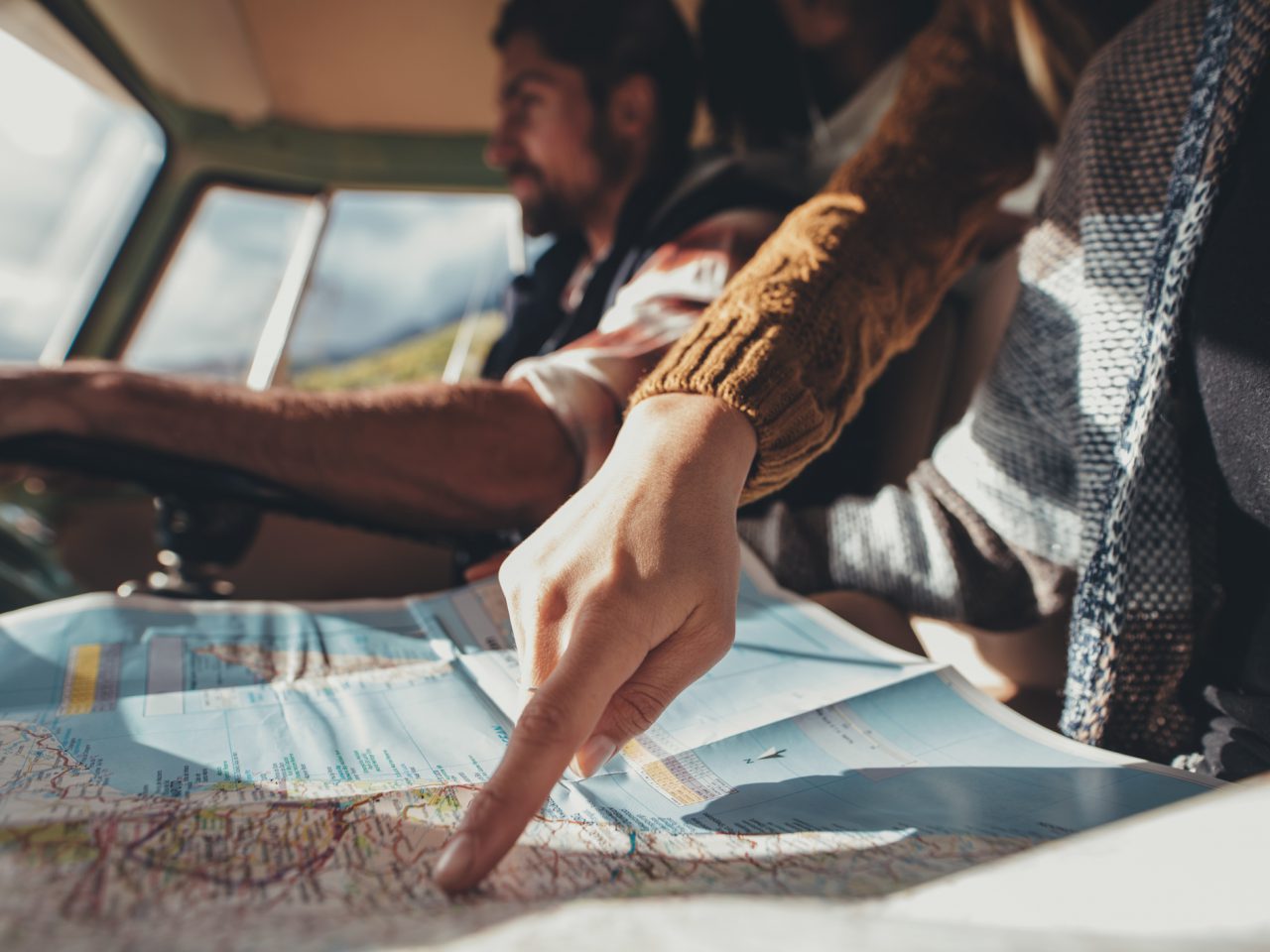 Twee mensen wijzen tijdens een roadtrip in een auto naar een kaart.