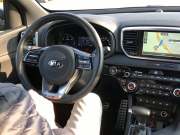 Er zit een man op de bestuurdersstoel van een Kia Sportage.