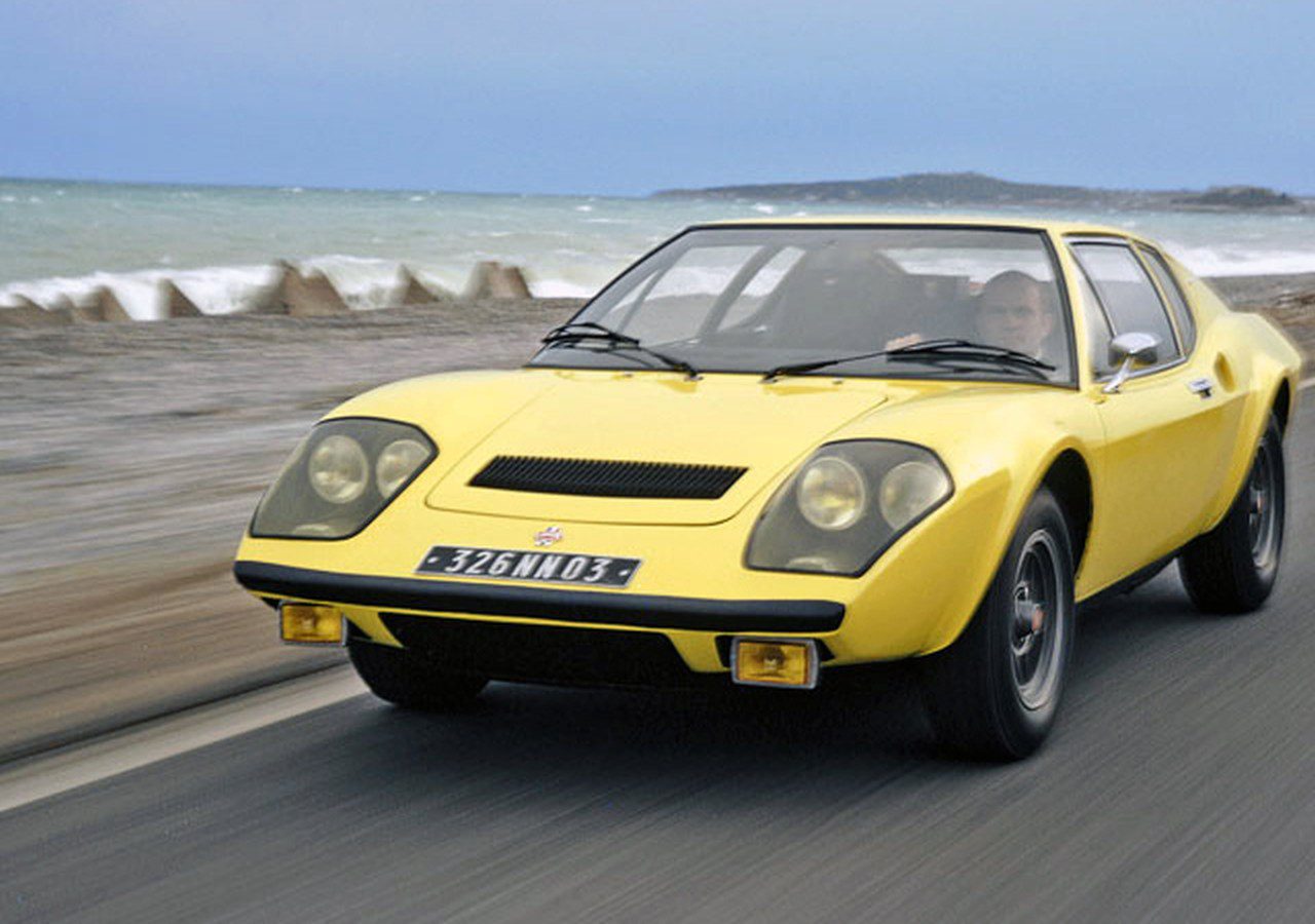 Een Ligier-sportwagen rijdt over een weg vlakbij de oceaan.