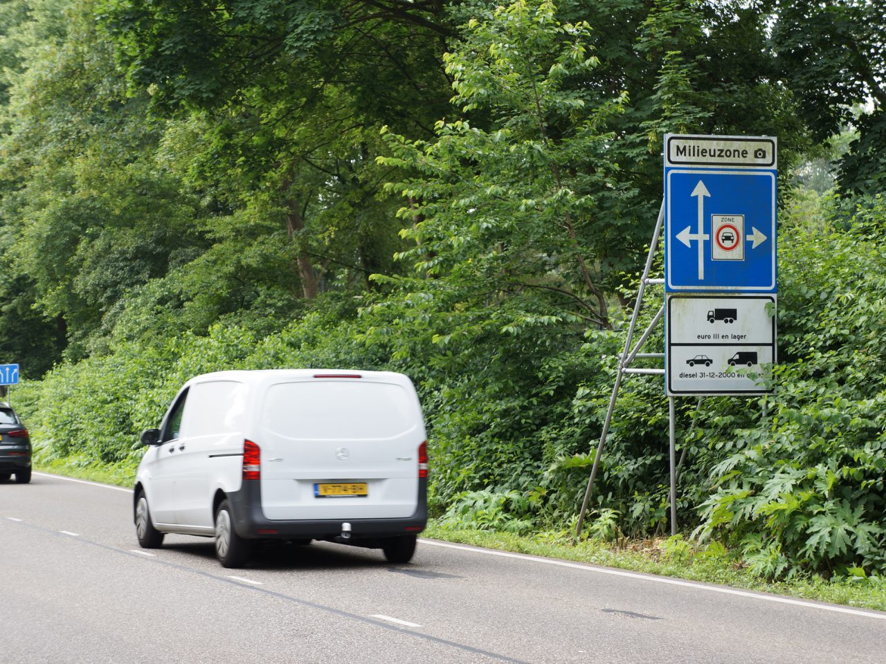 Een wit busje rijdt over de milieuzoneweg.