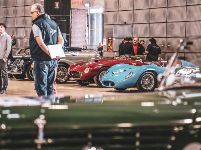 Een groep mensen kijkt naar oldtimers in een garage, ter voorbereiding op Mille Miglia 2019.