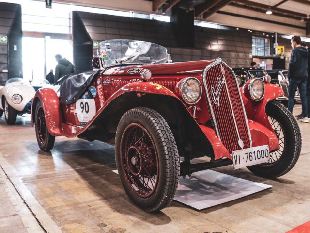 Een rode vintage auto, deelnemer aan de Mille Miglia 2019, staat geparkeerd in een garage.
