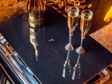 Twee glazen champagne op een tafel naast een open haard, die lijkt op de luxe van een Rolls-Royce-interieur.