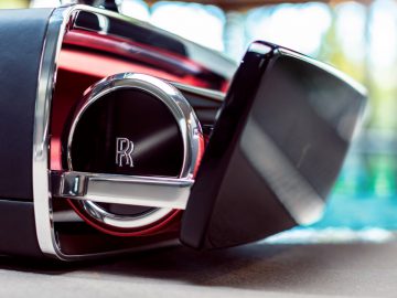 Een zwart-zilveren Rolls-Royce-radio op een tafel naast een zwembad.