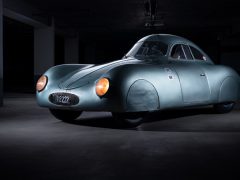 Een vintage Porsche Type 64 staat geparkeerd in een donkere garage.