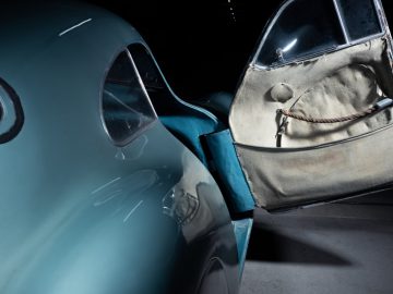 Een blauwe Porsche Type 64 met de deur open in een donkere kamer.