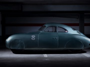Een groene vintage Porsche Type 64 staat geparkeerd in een donkere garage.