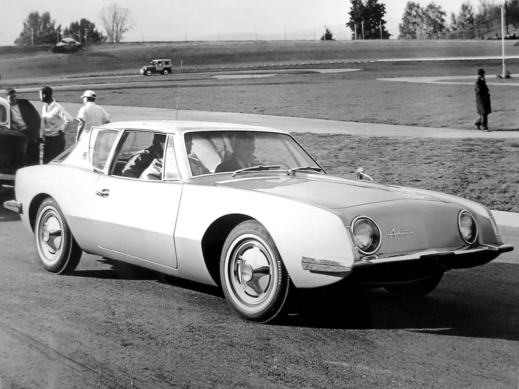 Een zwart-witfoto van een man die in een Studebaker Avanti rijdt.