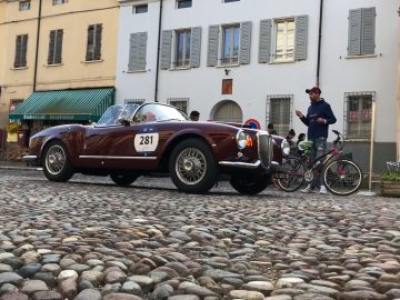 Een klassieke auto van de Mille Miglia 2019 staat geparkeerd op een geplaveide straat.