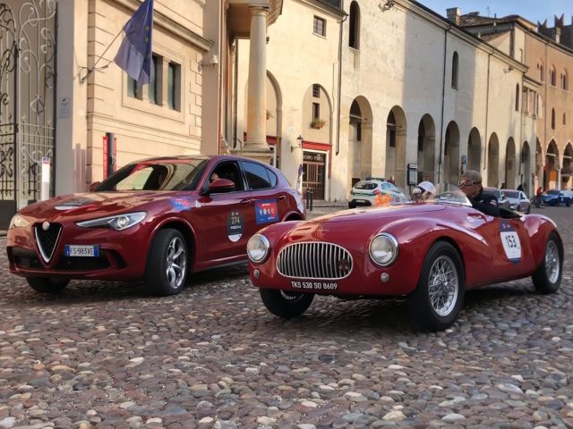 Twee klassieke auto's geparkeerd op een geplaveide straat tijdens de Mille Miglia 2019.