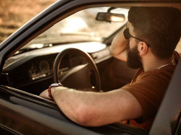Een man zit op de warme bestuurdersstoel van een auto.