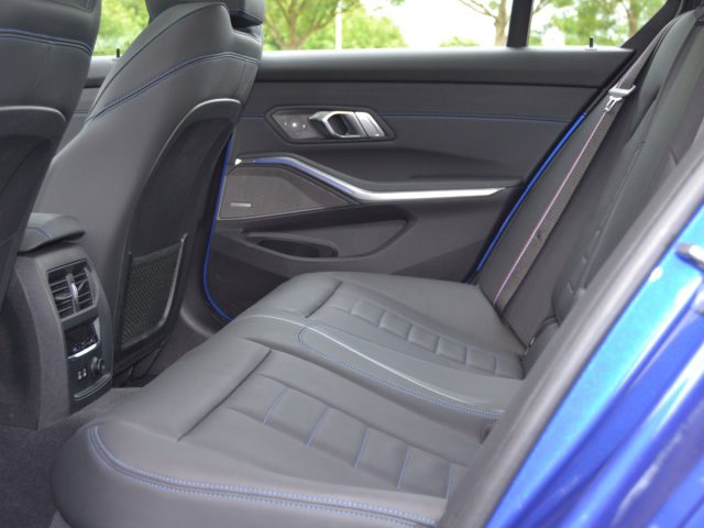 Het interieur van een blauwe 3 Serie-auto met zwarte stoelen.