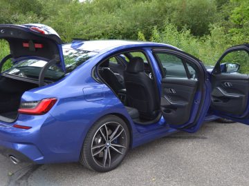 De blauwe BMW 3 Serie M3 sedan heeft de deuren open.