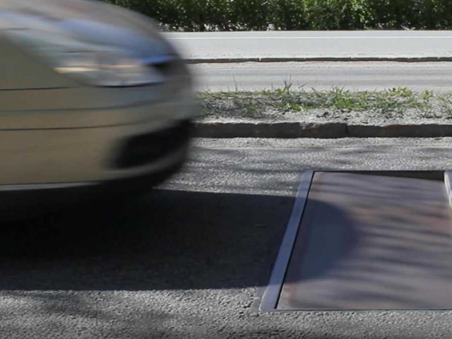 Een auto rijdt door een straat in Duitsland met een gat in de grond.