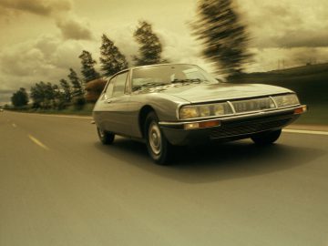 Een Citroën SM die over de weg rijdt.