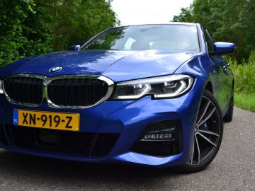 De blauwe BMW 3-serie staat geparkeerd op een weg.