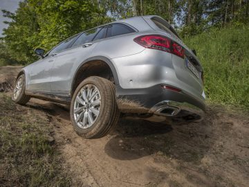 De Mercedes-Benz GLC SUV rijdt over een onverharde weg.