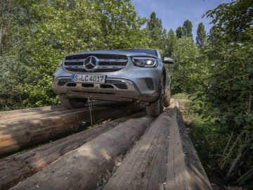 Mercedes-Benz G-Klasse op boomstammen in het bos.