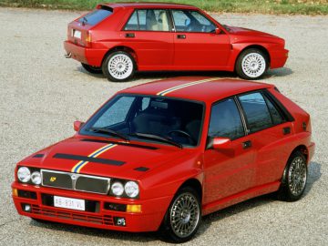 Twee rode Lancia Delta-auto's geparkeerd naast elkaar.