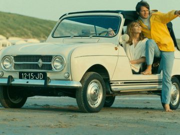 Een man en een vrouw zitten in een Renault op het strand.