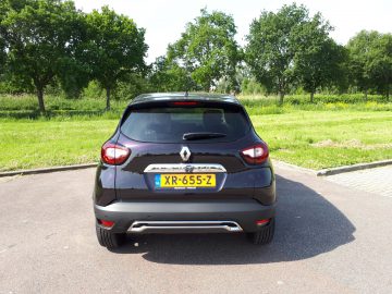 Een zwarte Renault Captur geparkeerd op een parkeerplaats.
