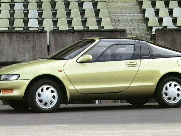 Voor een leeg stadion staat een groene Toyota-auto geparkeerd.