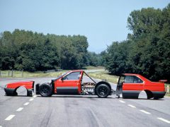 Een rode Alfa Romeo 164 op een weg.