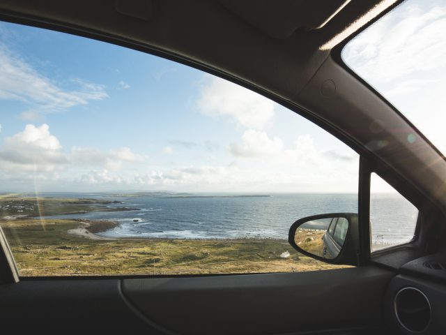 Een zicht op de oceaan door een autoraam in Ierland.
