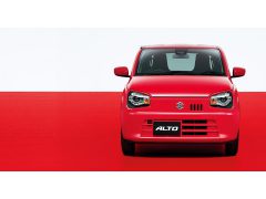 Een kleine rode Suzuki Alto staat geparkeerd op een rode achtergrond.