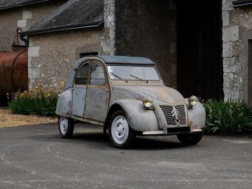 Een oude roestige Citroën geparkeerd voor een schuur.