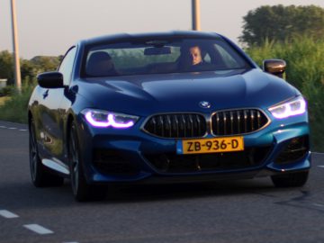 Een BMW die over een landweg rijdt.