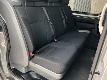 De achterbank van een Nissan NV300 met zwart lederen stoelen.