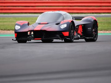 Een zwart-rode Aston Martin Valkyrie op een circuit.