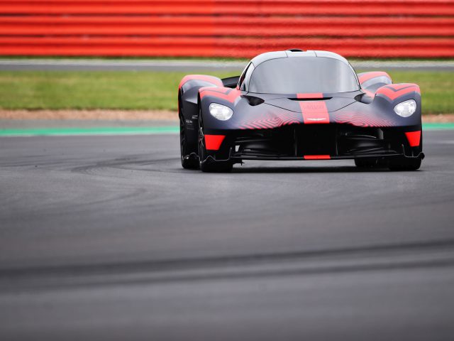 Een rode en zwarte Aston Martin Valkyrie-raceauto op een circuit.