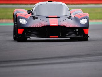 Een zwarte en rode Aston Martin Valkyrie-raceauto op een circuit.