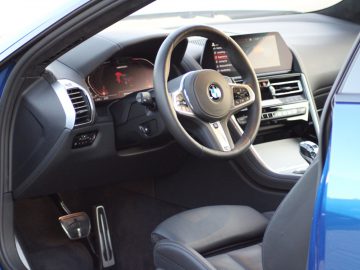 Het interieur van een blauwe BMW-auto met lederen stoelen en stuurwiel.